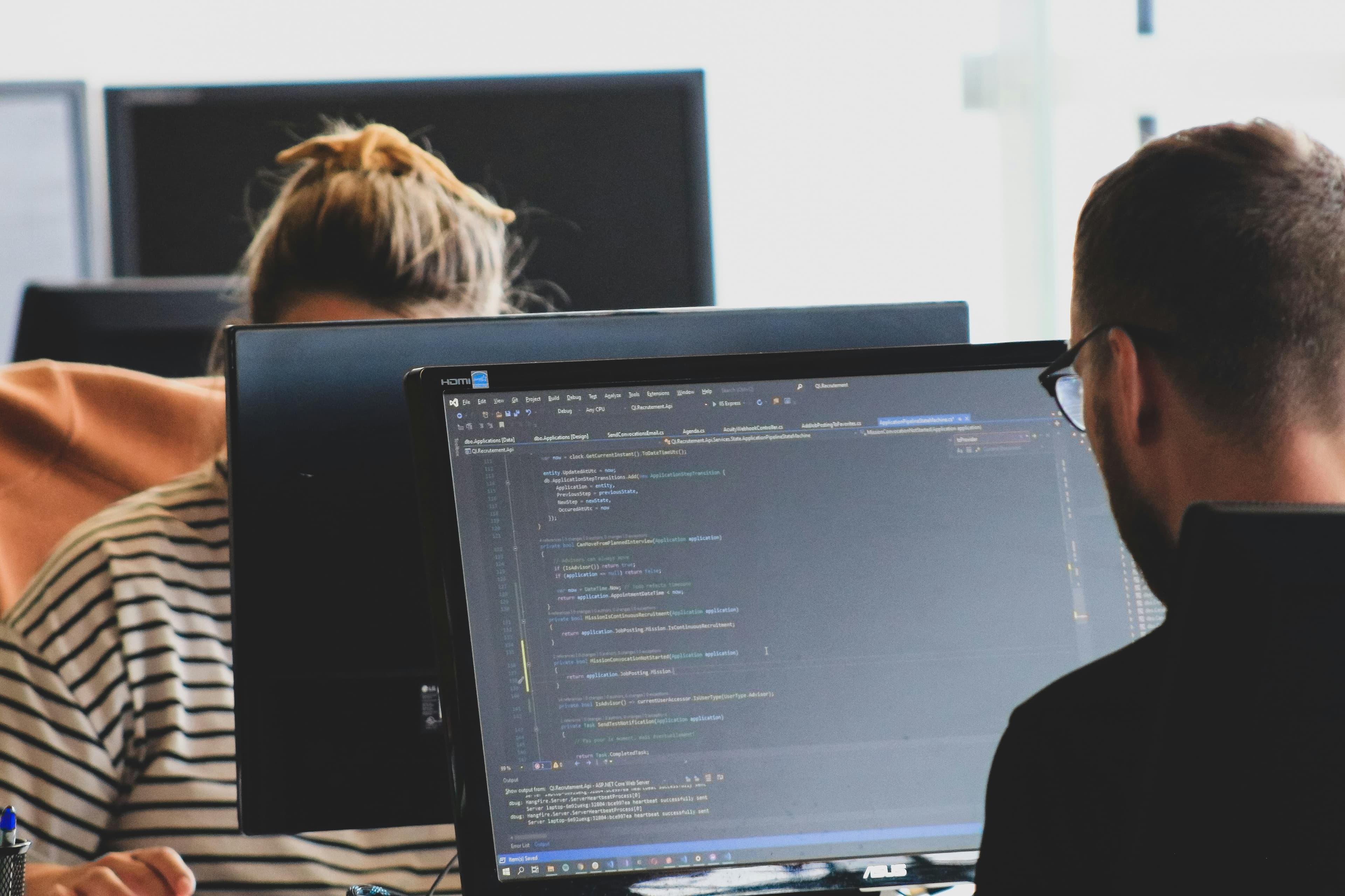 Two developers working on application code at their monitors