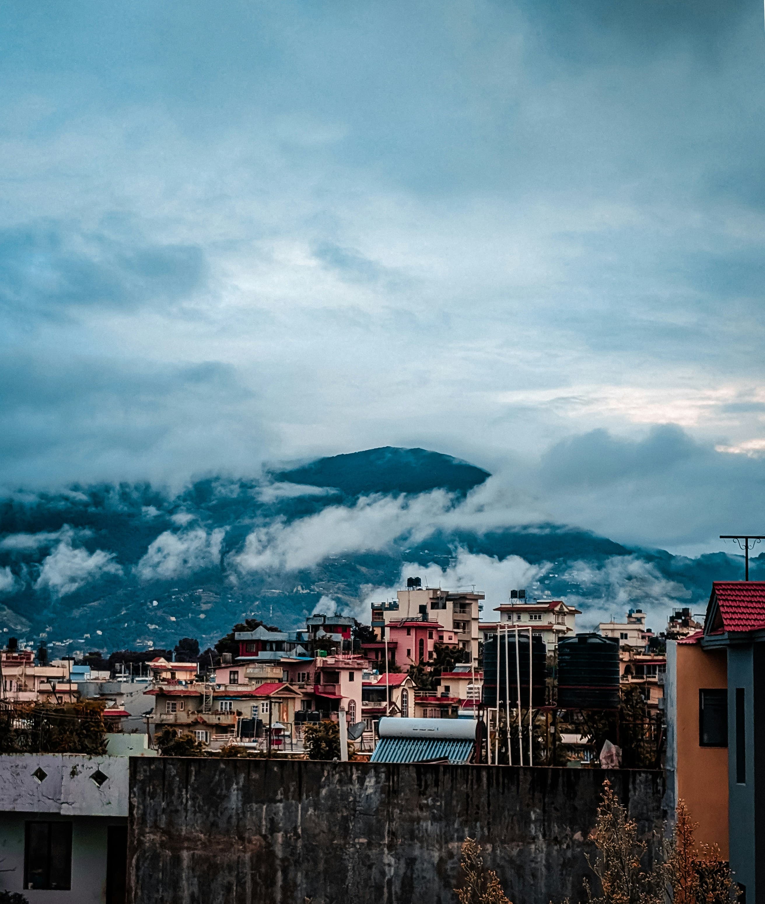 Houses of a hillside town beneath cloud-covered hills